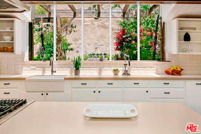 Панорамные окна на кухне с видом на задний двор с бассейном