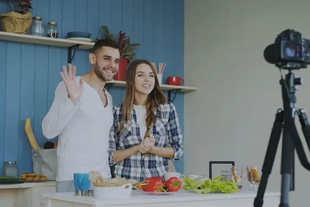 Пара блогеров записывает ролик на кухне и машет в камеру